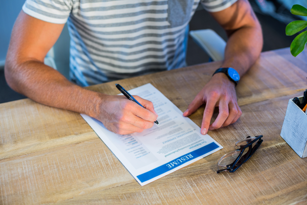 Man writing curriculum vitae at his desk